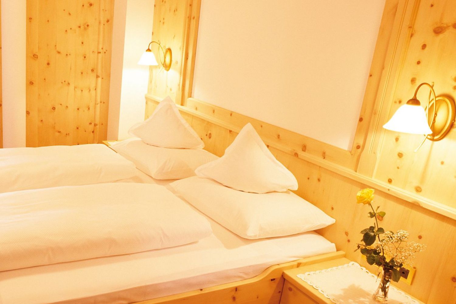 Hell eingerichtetes Schlafzimmer mit Doppelbett, Holzmöbeln und Zugang zu Balkon mit Sitzbereich.