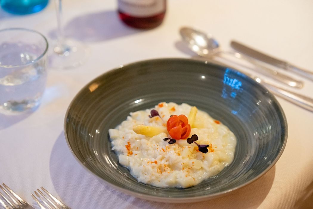Elegantes Spargelrisotto mit Tomatendekoration in grüner Schüssel auf gedecktem Tisch