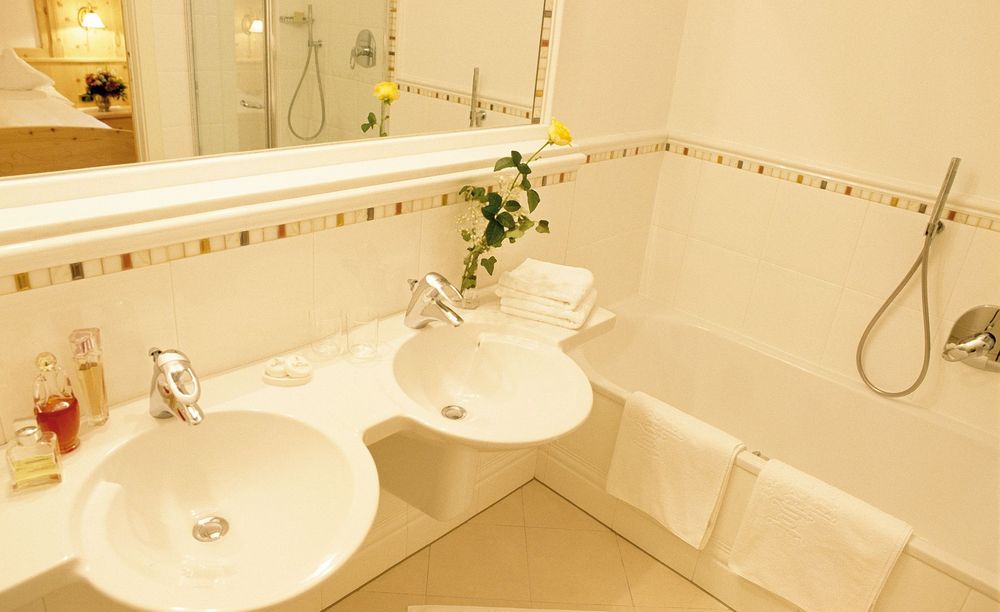 Bagno moderno con doppio lavabo, vasca, asciugamani bianchi e specchio grande