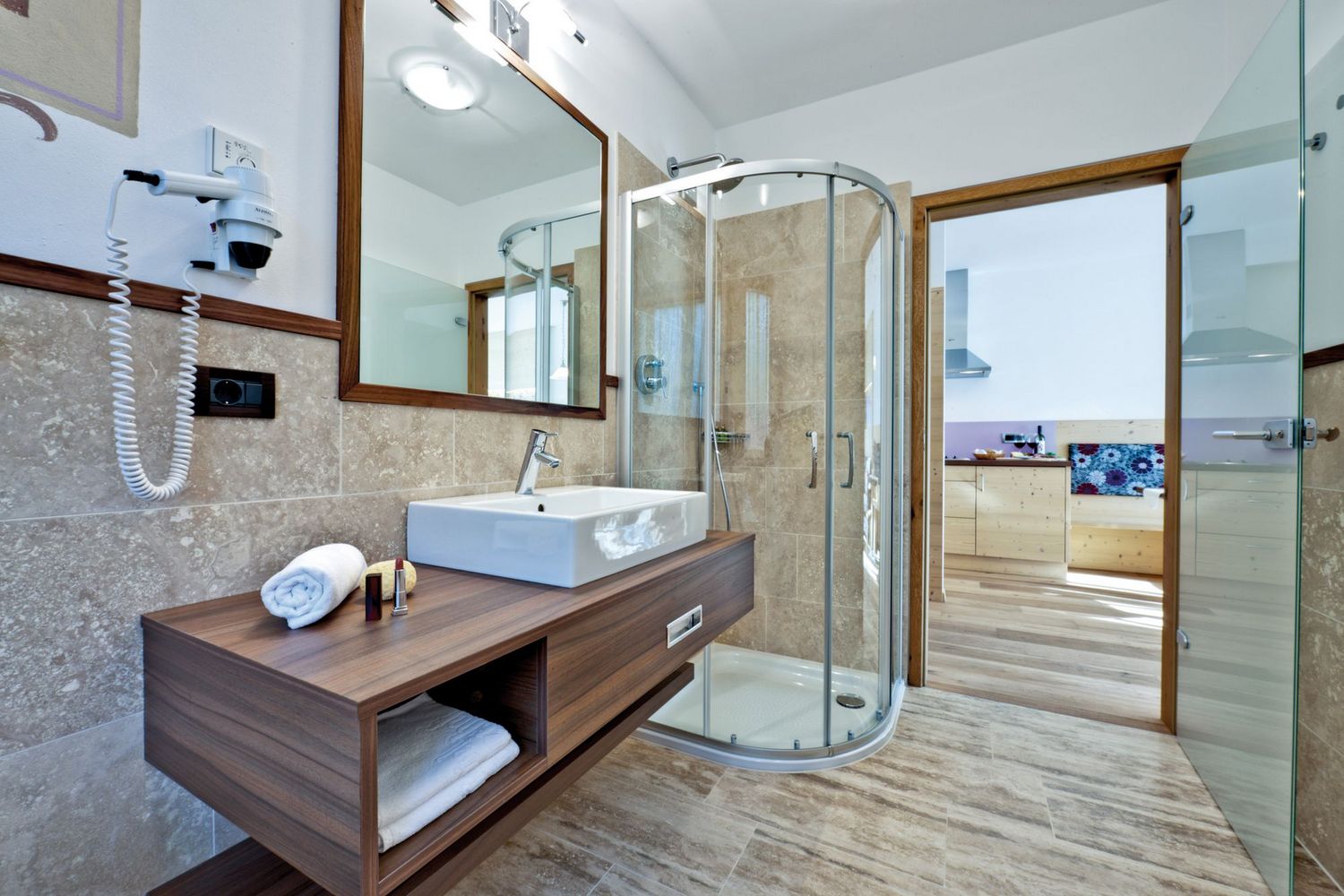 Modernes Badezimmer mit Dusche, Waschbecken auf Holzwaschtisch, Handtuch und Kosmetikartikeln