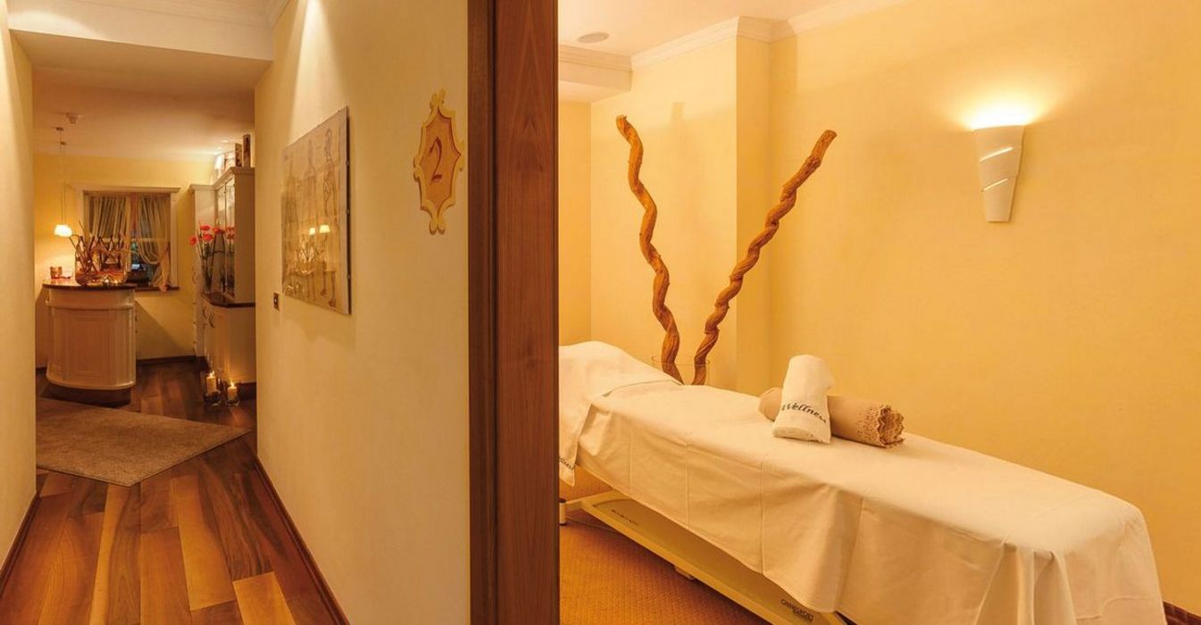 Cozy spa hallway leading to a treatment room with a massage table and warm yellow lighting