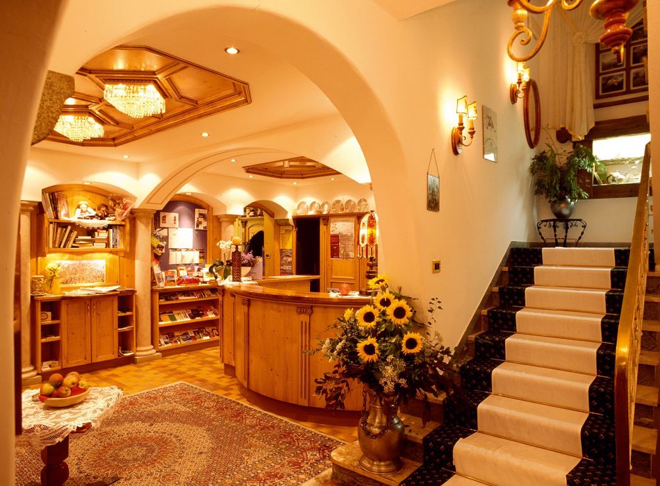 Warme, einladende Hotelrezeption mit Holzmöbeln, Sonnenblumen und Treppe mit Läuferteppich